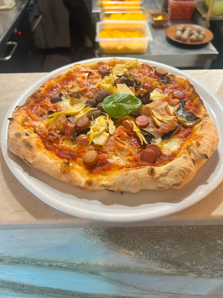 Pizza Capricciosa su piatto bianco, sul banco di marmo